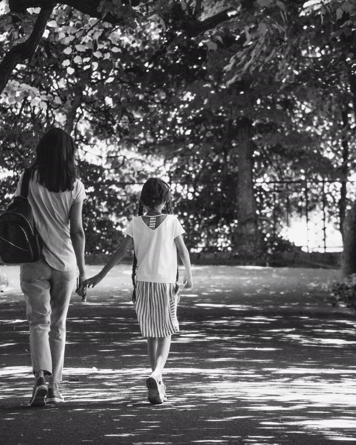 Madre e hija caminan de la mano por un sendero, en blanco y negro (foto de demostración)
